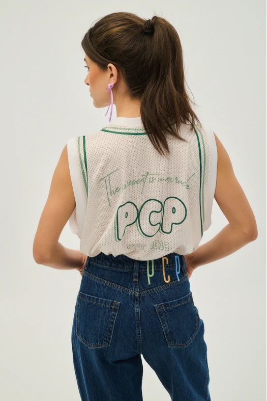 Woman wearing a sleeveless shirt with 'PCP' branding on a plain background