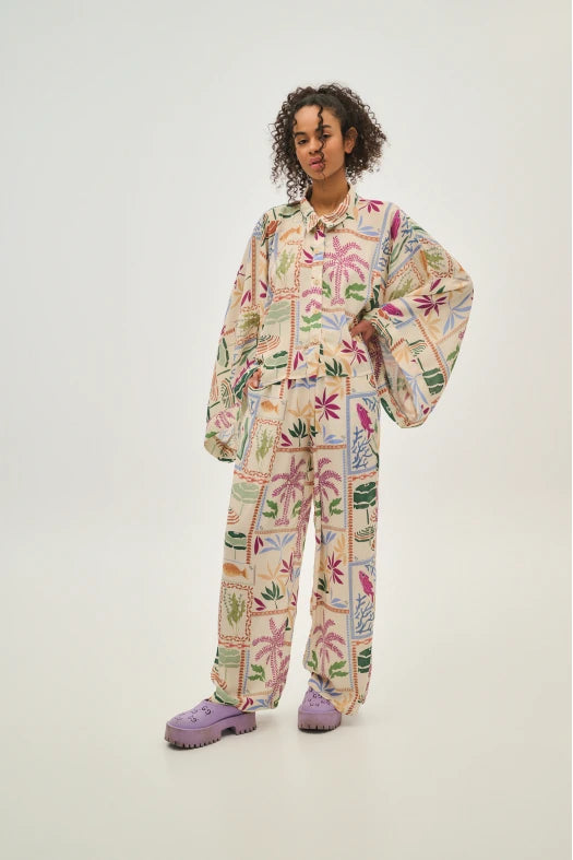 Person wearing a colorful floral patterned outfit on a plain background