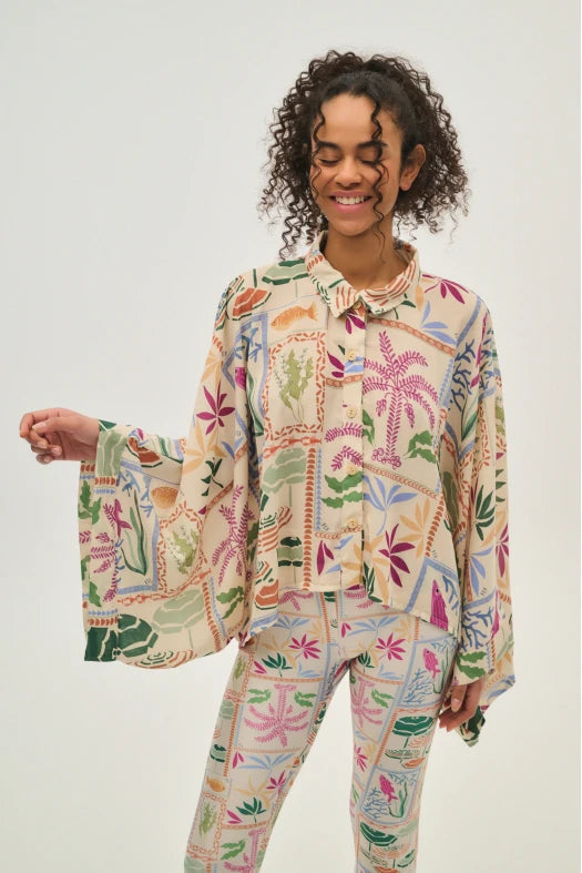 Person wearing a colorful floral patterned outfit on a plain background