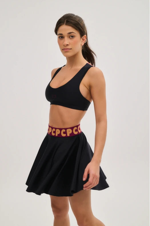 Woman wearing a black sports bra and skirt with red text on a white background
