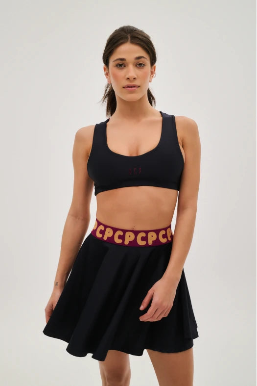 Woman wearing a black sports bra and skirt with red text on a white background