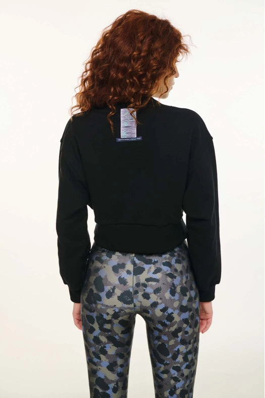 Person wearing a black sweatshirt and camouflage pants on a white background