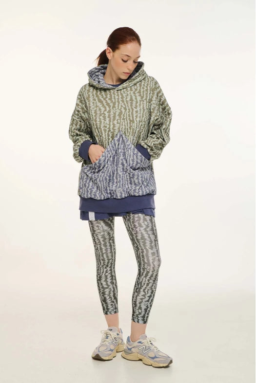 Person wearing a patterned hoodie and leggings on a white background