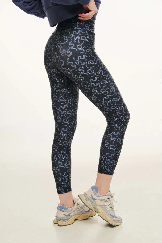 Person wearing dark blue patterned leggings on a white background