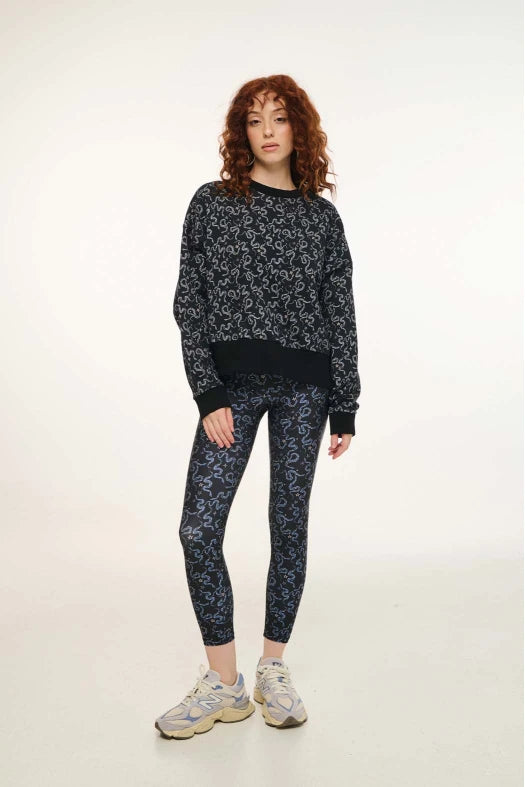 Woman wearing a black floral sweatshirt and leggings on a white background
