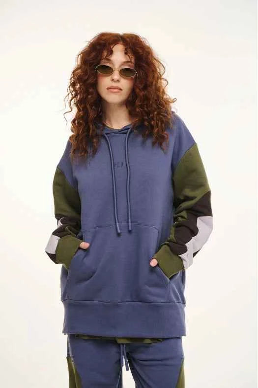 Person wearing a blue and green hoodie with a plain background