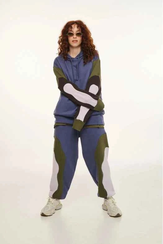 Person wearing a blue and green tracksuit with white accents on a white background