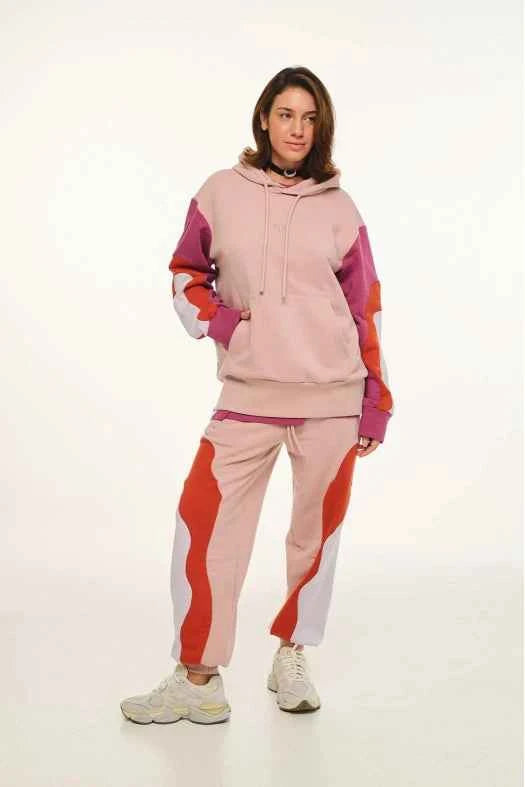 Person wearing a colorful tracksuit with pink, orange, and purple hues on a white background