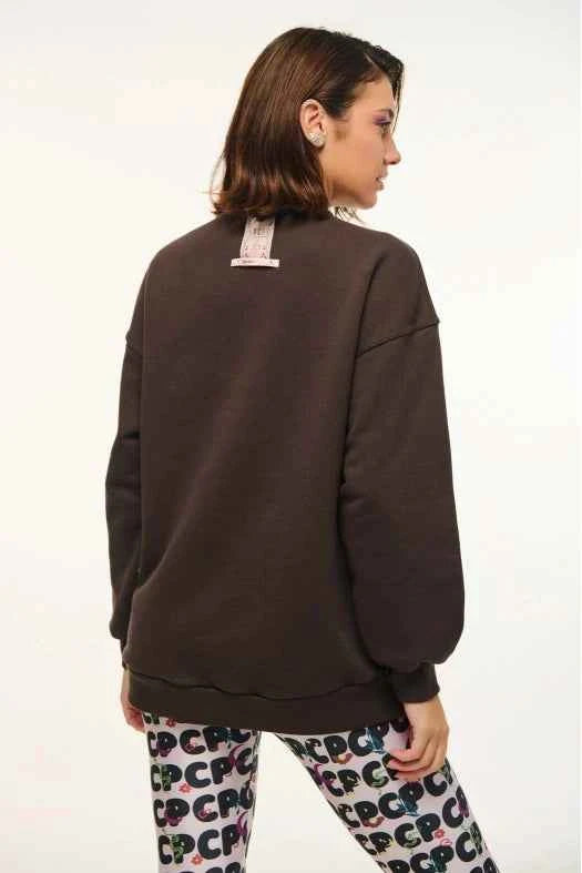 Person wearing a dark brown sweatshirt and patterned pants on a white background