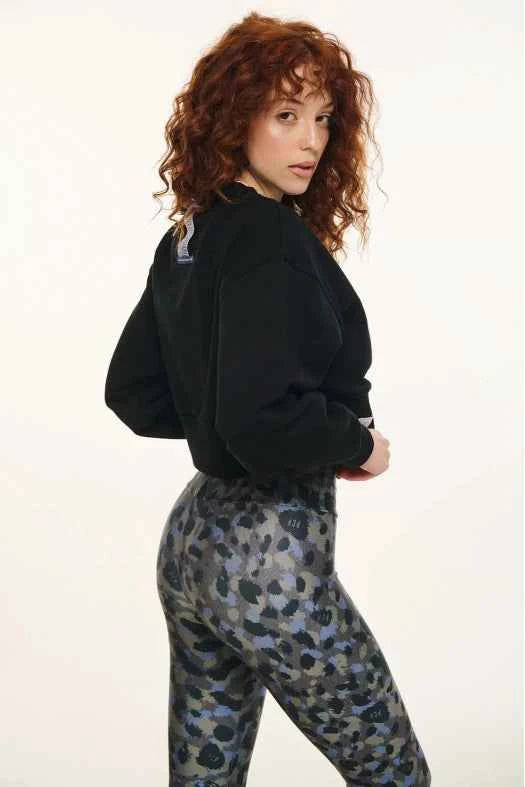 Person wearing a black jacket and camouflage pants on a white background