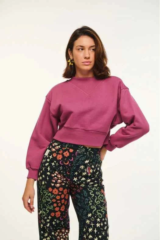 Woman wearing a pink sweater and colorful pants on a white background