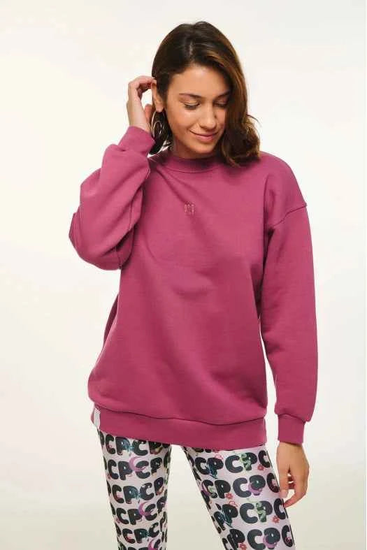 Woman wearing a pink sweatshirt and patterned pants on a white background