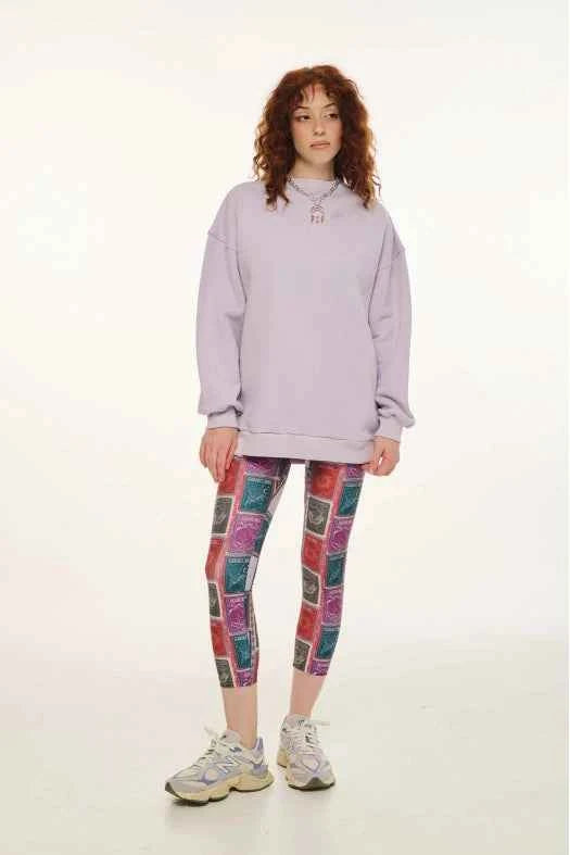 Person wearing a light purple hoodie and patterned leggings on a white background