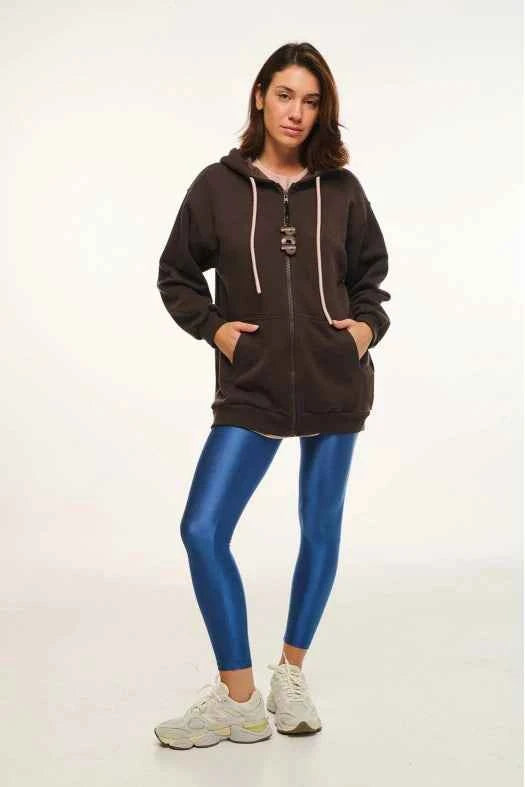 Person wearing a brown zip-up hoodie and blue leggings on a white background