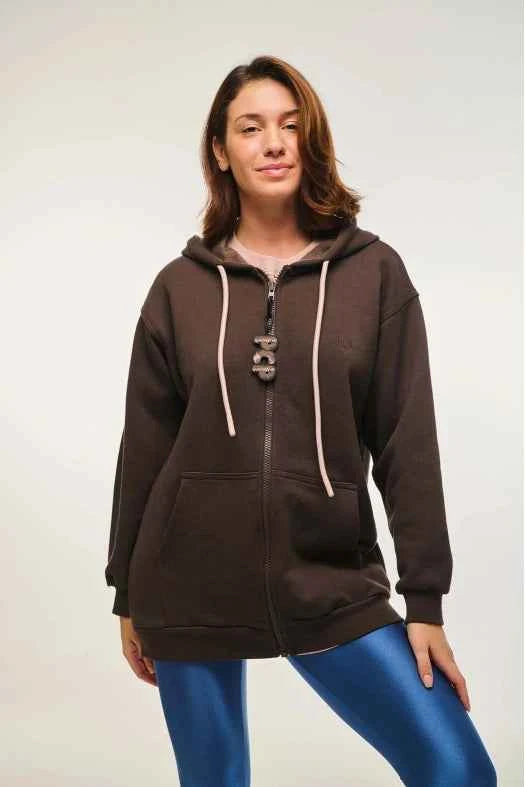 Woman wearing a brown hoodie with a white zipper on a plain background
