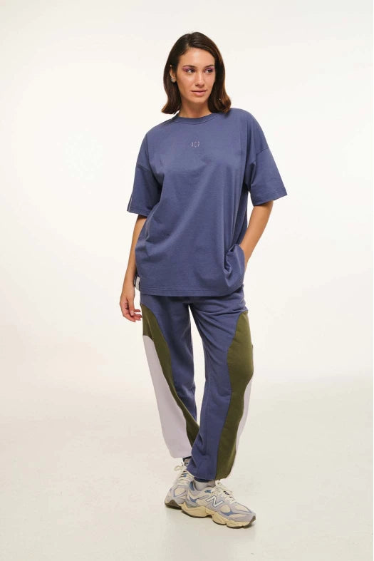 Person wearing a blue oversized t-shirt and tracksuit with a white background