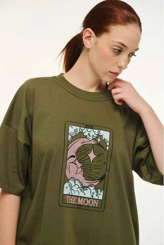 Person wearing a green t-shirt with a graphic design and text 'THE MOON' on a white background