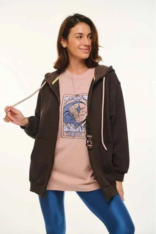 Woman wearing a brown hoodie over a pink graphic t-shirt on a white background