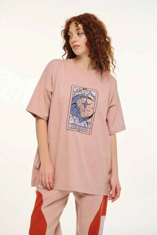 Person wearing a pink oversized t-shirt with a graphic design on a white background