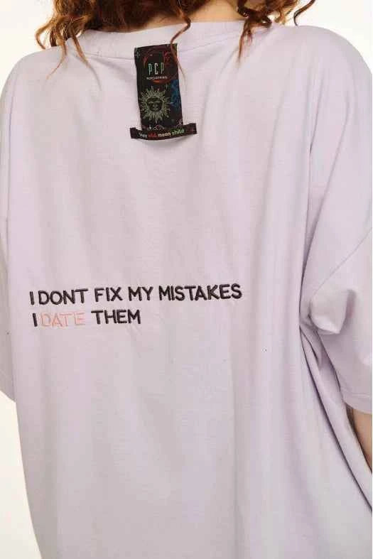 White t-shirt with text on the back, worn by a person, with a visible brand label.