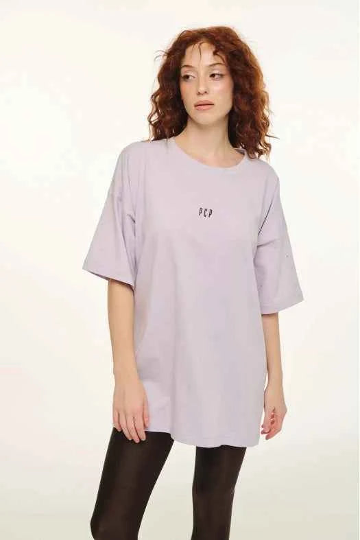 Woman wearing a light purple oversized t-shirt with text on a white background