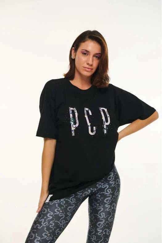 Woman wearing a black t-shirt with 'PCP' design and patterned leggings on a white background