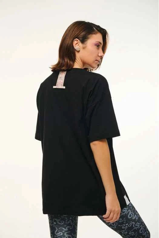 Person wearing a black oversized t-shirt with floral patterns on a white background