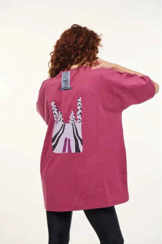 Person wearing a pink t-shirt with a zebra design on the back, standing against a white background
