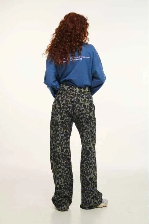 Person wearing a blue sweatshirt and patterned pants on a white background
