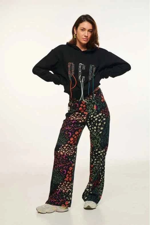 Person wearing a black hoodie and colorful patterned pants on a white background