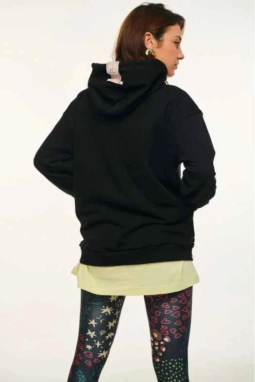 Person wearing a black hoodie with colorful leggings on a white background