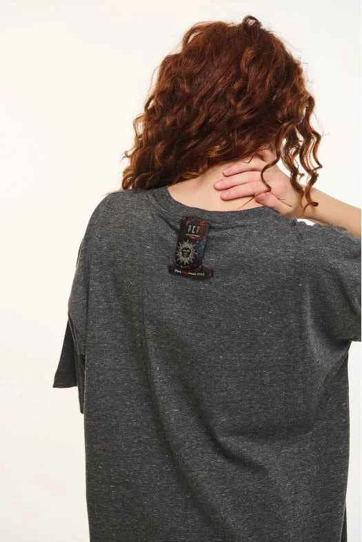 Person wearing a gray t-shirt with a brand logo on the back, against a plain background