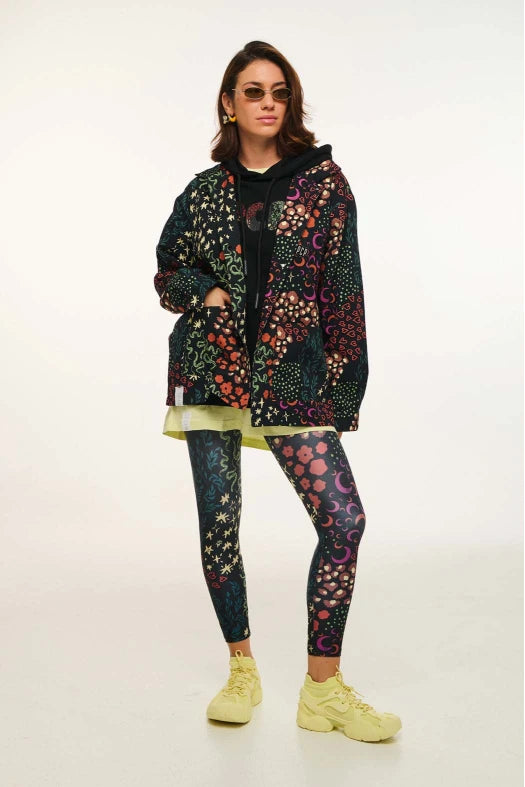 Person wearing a colorful patterned jacket and leggings with yellow shoes on a white background