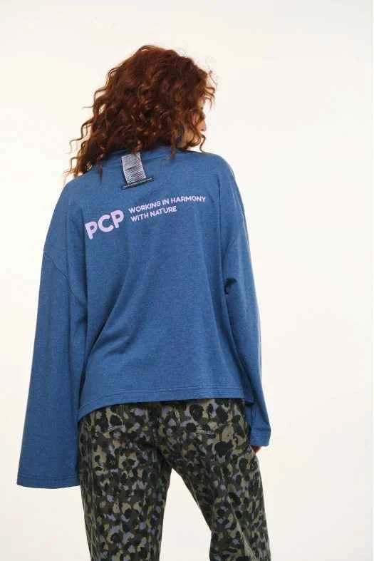 Person wearing a blue sweatshirt with 'PCP' branding on the back, standing against a white background.