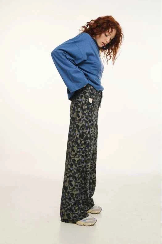 Person wearing a blue sweatshirt and leopard print pants on a white background