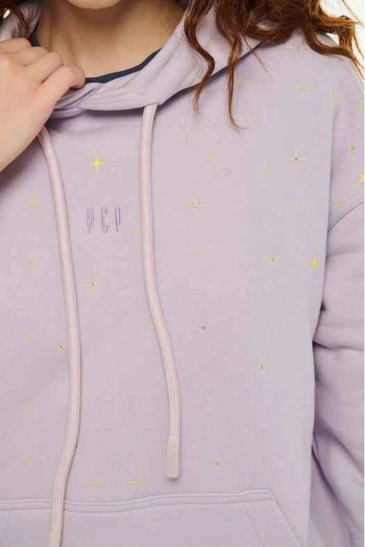 Close-up of a lavender hoodie with star patterns and a brand logo.