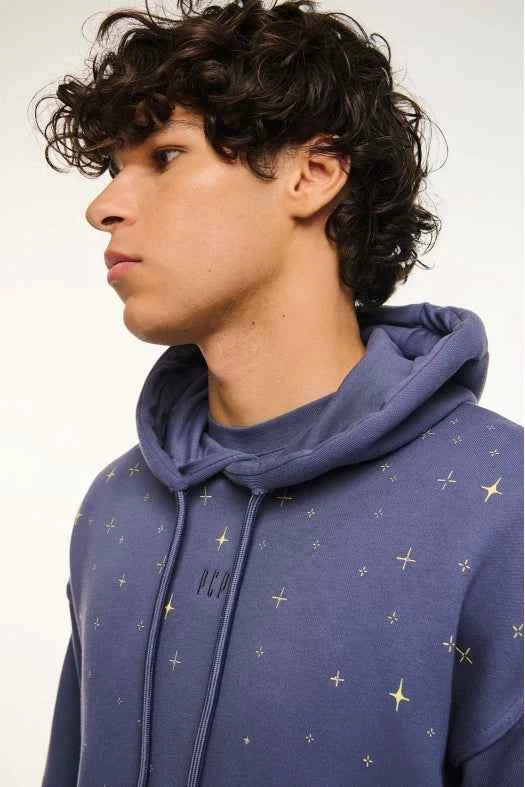 Person wearing a blue hoodie with star patterns on a plain background