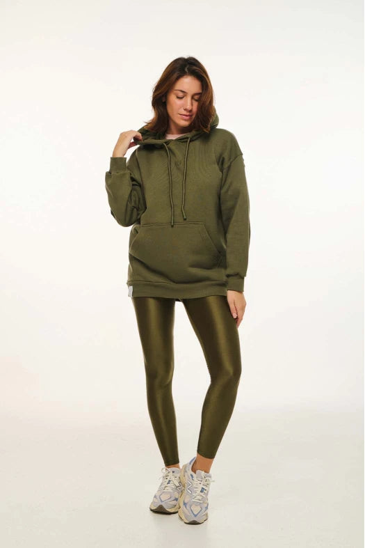 Woman wearing an olive green hoodie and leggings set on a white background