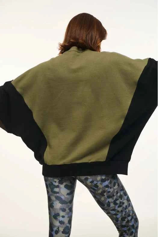 Person wearing a green and black jacket with patterned pants on a white background