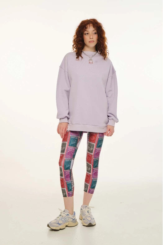 Person wearing a light purple hoodie and colorful patterned leggings on a white background