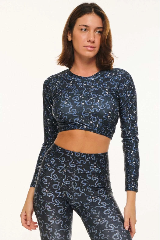 Woman wearing a dark blue patterned long-sleeve top and leggings on a white background