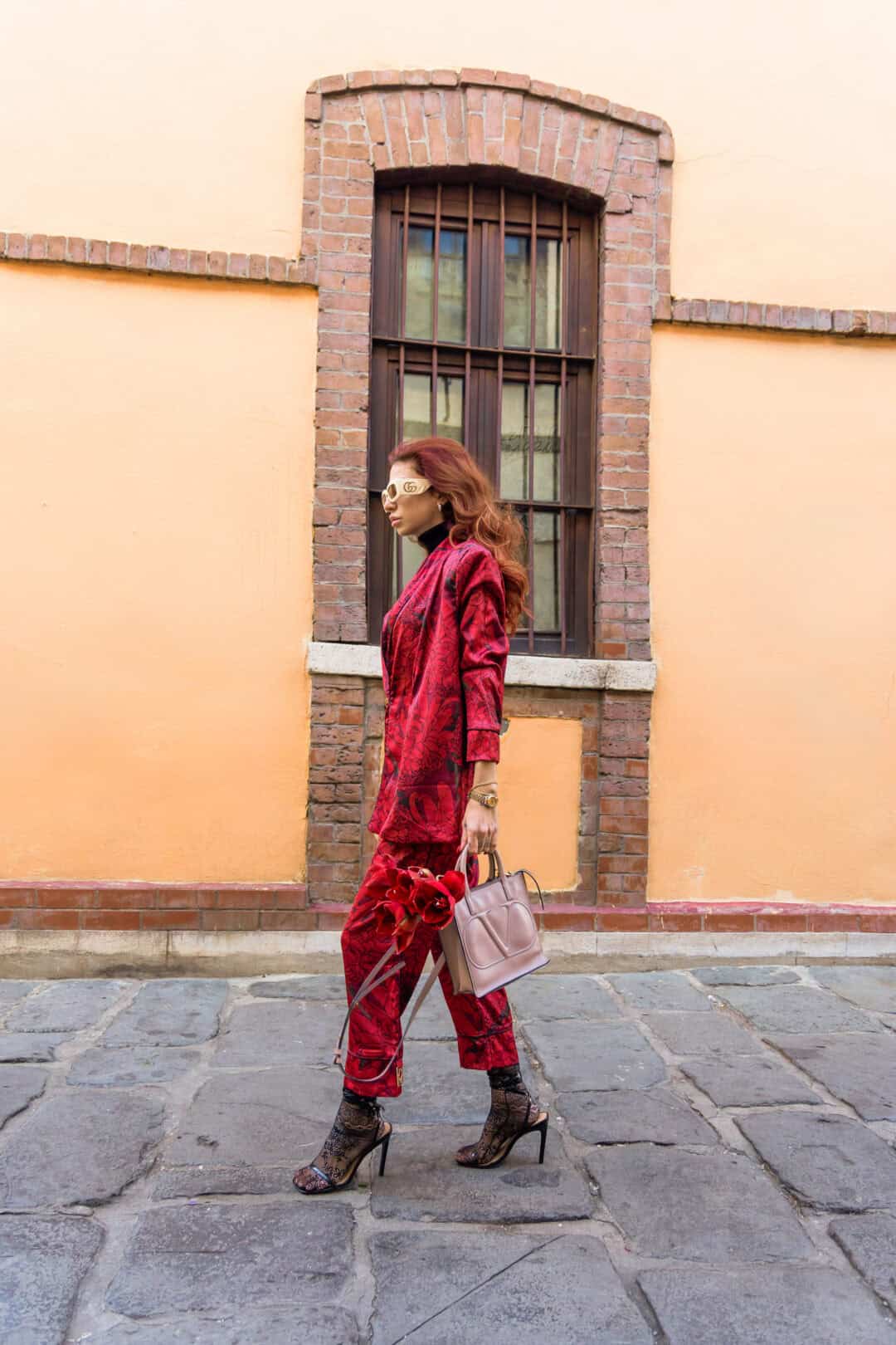 Woman in a red outfit walking on a street with a building in the background