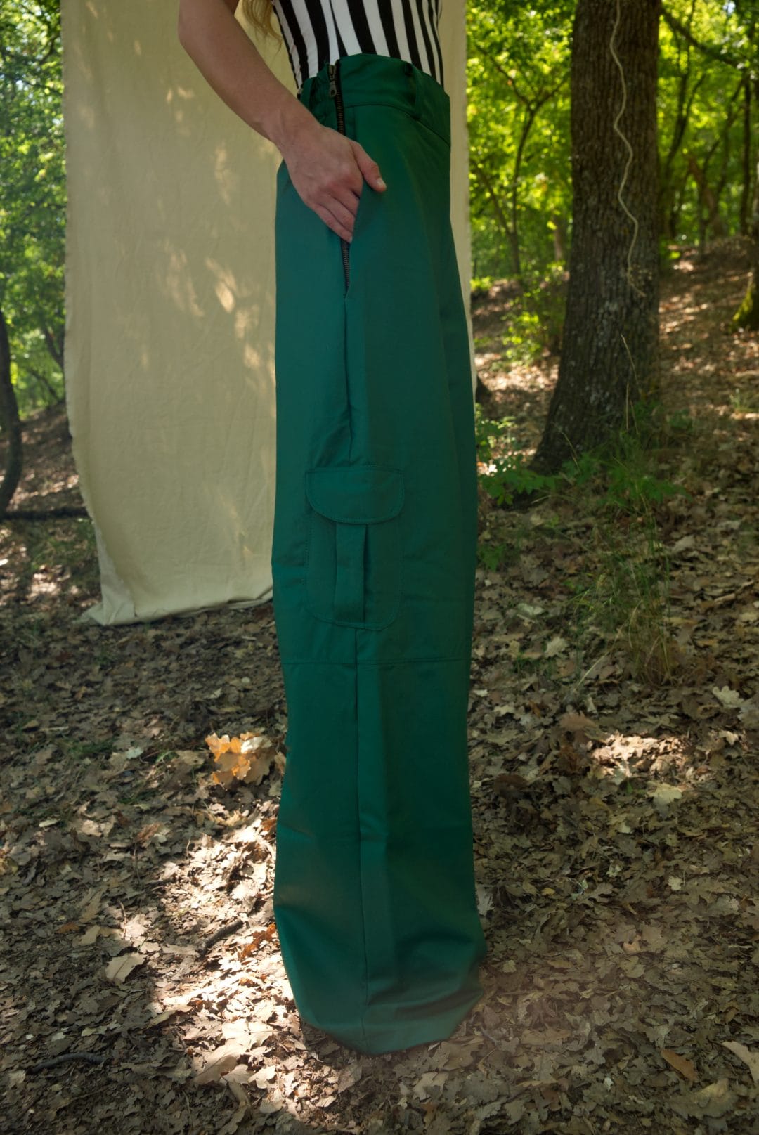Person wearing teal pants standing in a forest setting