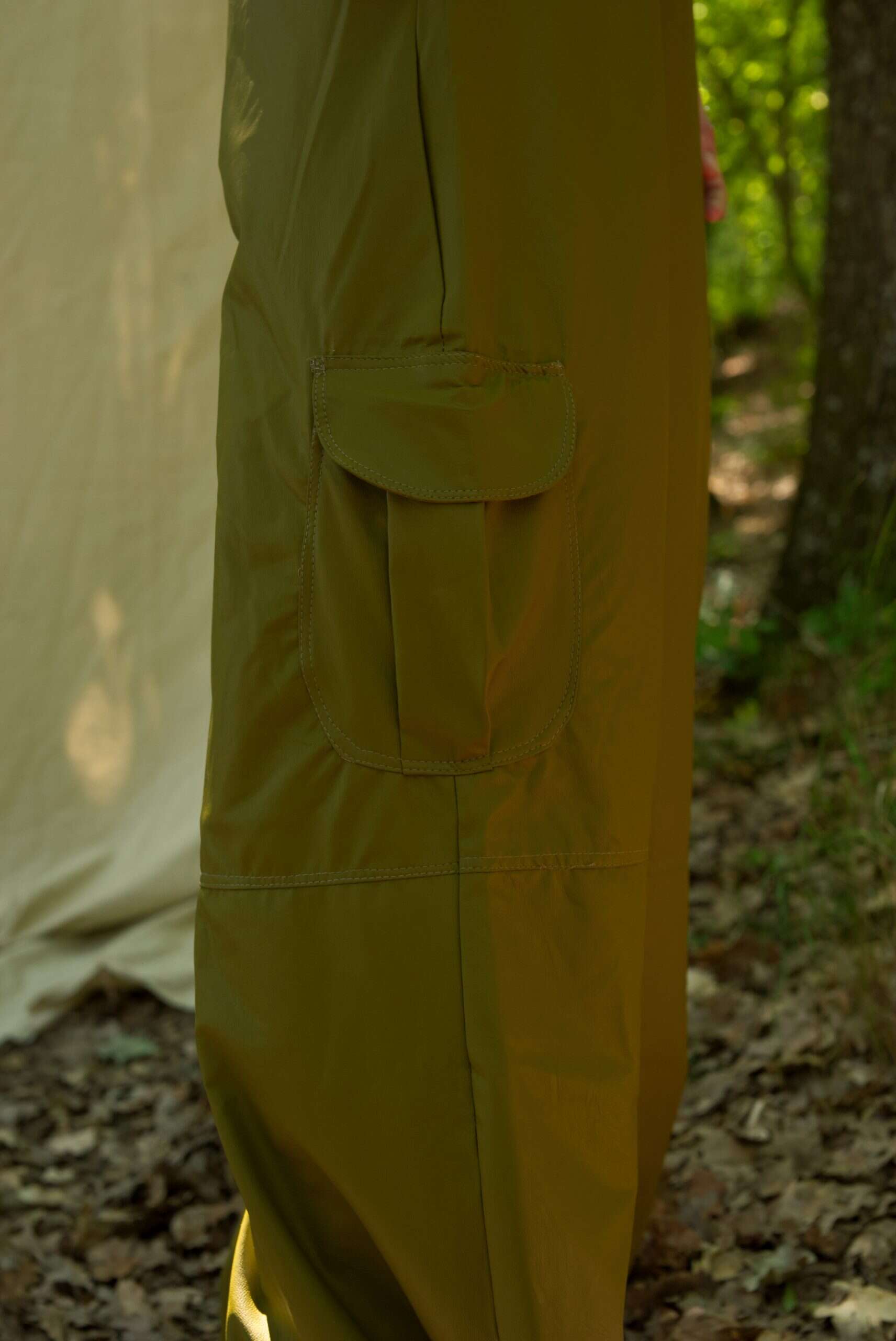 Yellow pants with a pocket in front of a tent in a forest setting