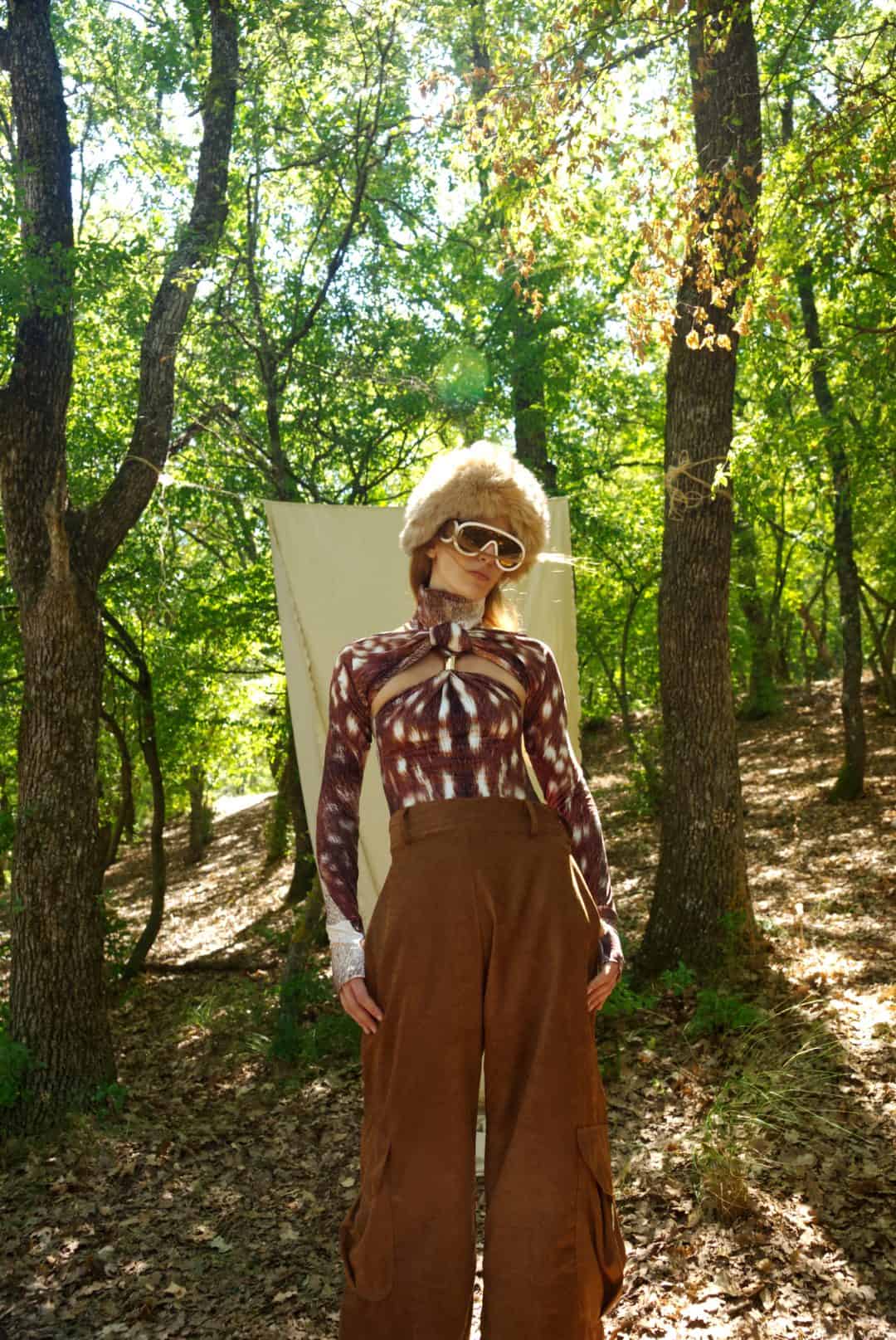 Person in a plaid shirt and brown pants standing in a forest