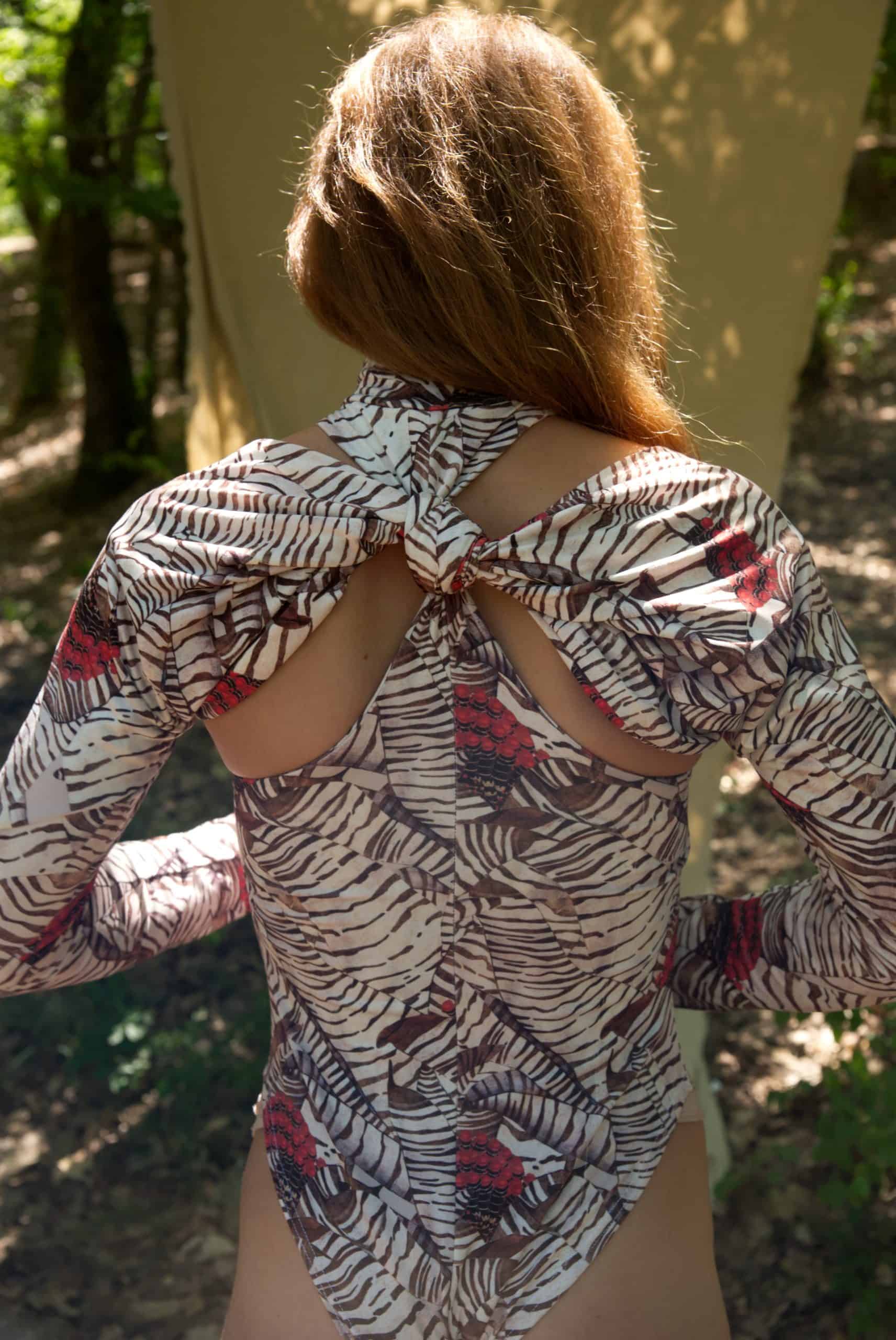 Person wearing a patterned blouse with open back in an outdoor setting