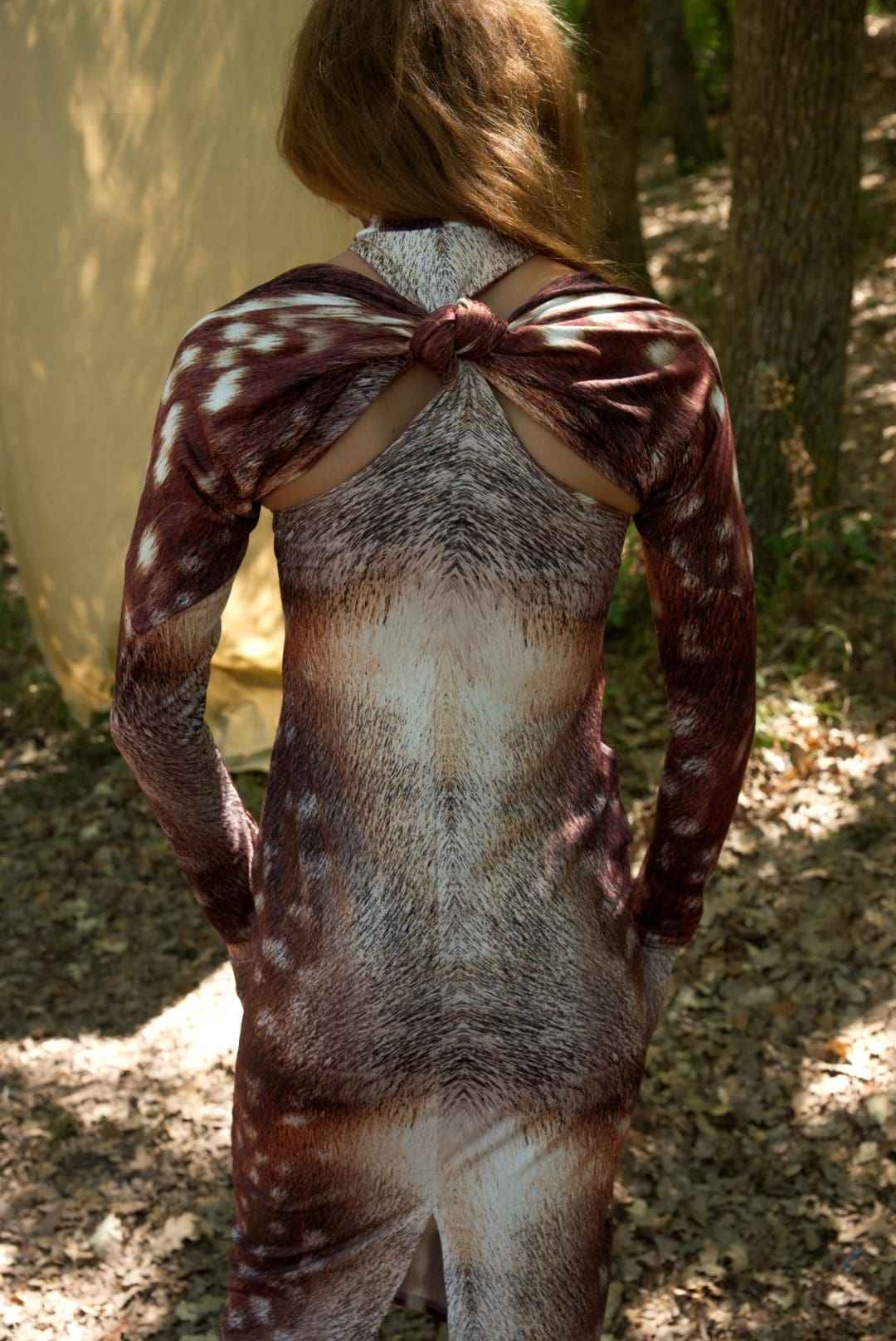 Person wearing a long-sleeve dress with a unique pattern outdoors.