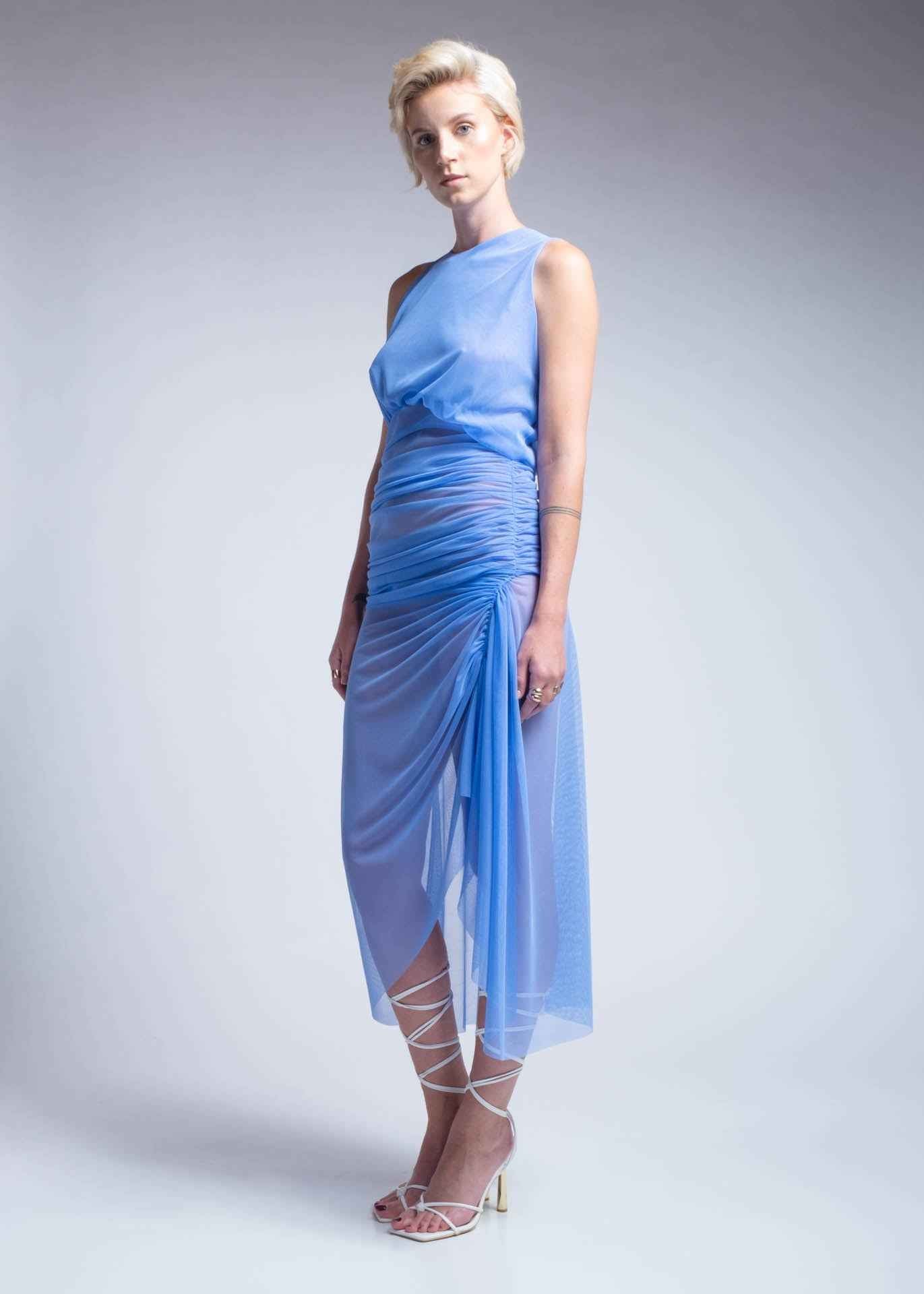 Woman wearing a light blue dress with a draped design on a plain background