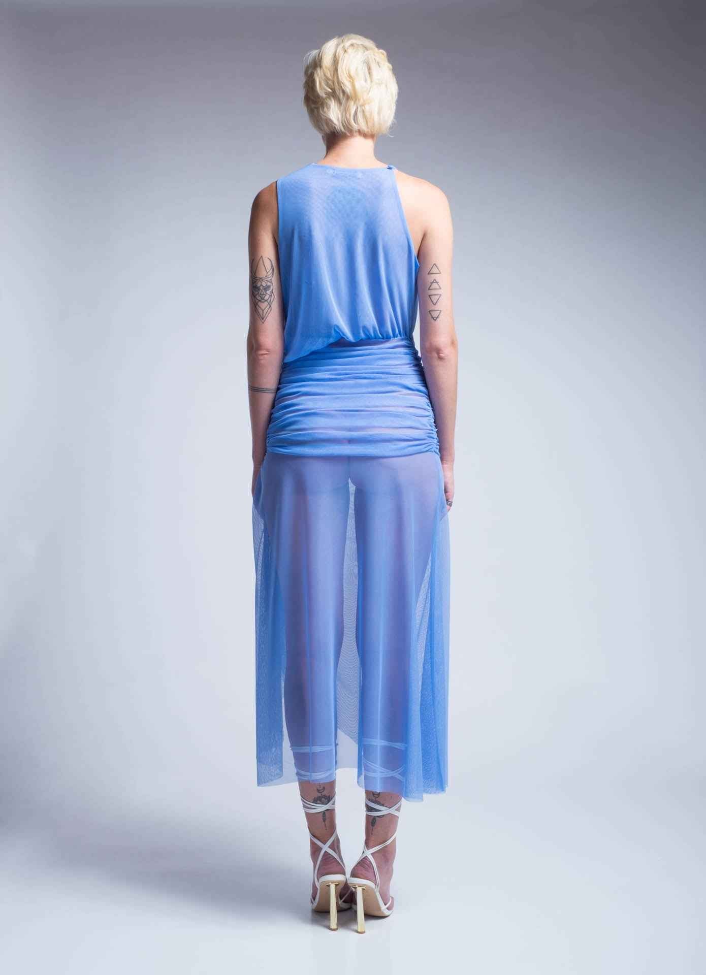 Woman wearing a blue dress with sheer overlay on a gray background