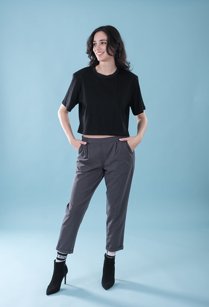 Woman wearing a black top and gray pants on a light blue background